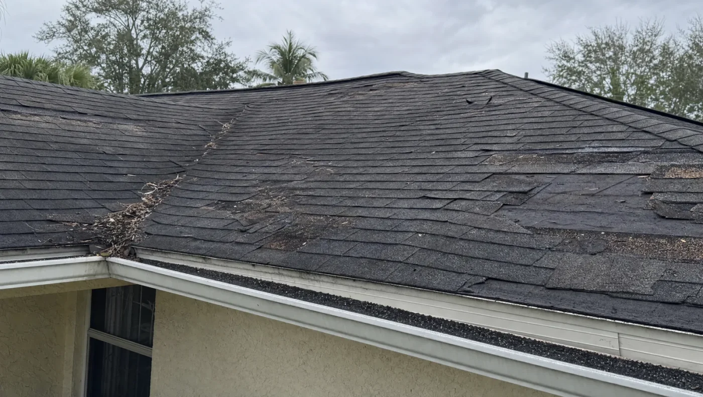 Aging asphalt shingle roof on a Florida home with curling shingles, missing sections, and algae streaks, before replacement by CMK Construction