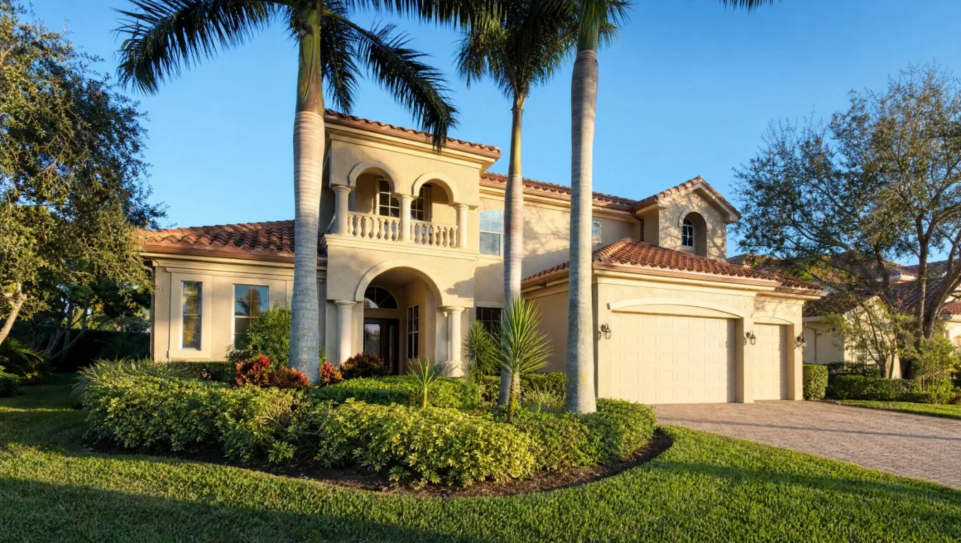 Two-story Mediterranean stucco home with a barrel tile roof, arched balcony, and royal palms in a Sarasota County planned community