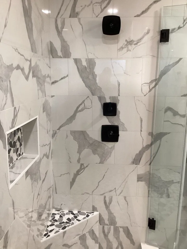 Shower niche and corner bench with pebble accent tile in marble look porcelain, Lutz bathroom remodel by CMK