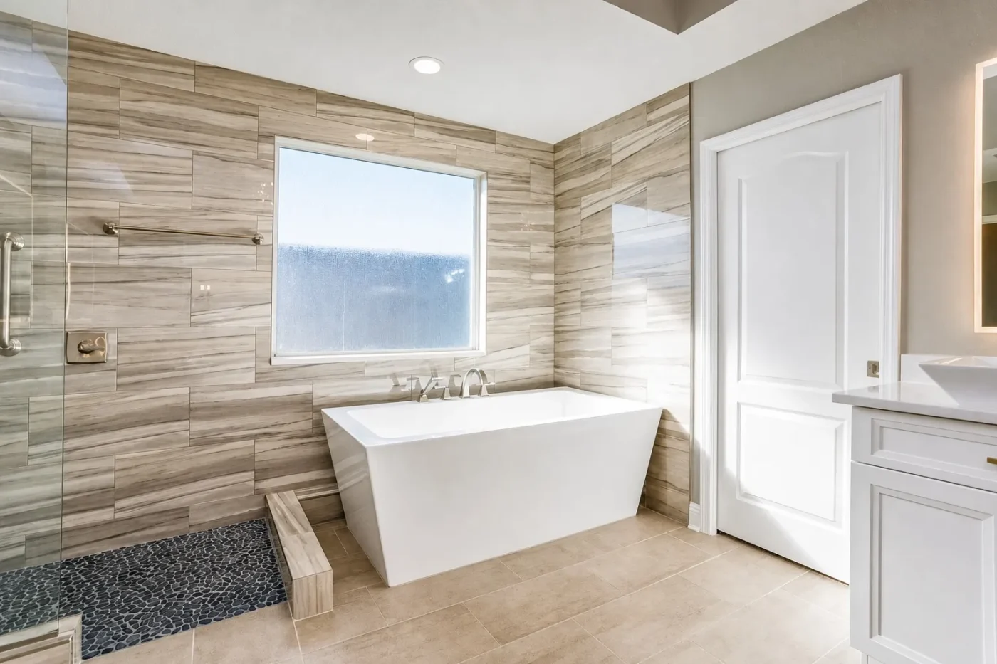 Spa style wet room bathroom with freestanding soaking tub, pebble stone shower floor, and large-format porcelain tile in Clearwater, Florida by CMK Construction