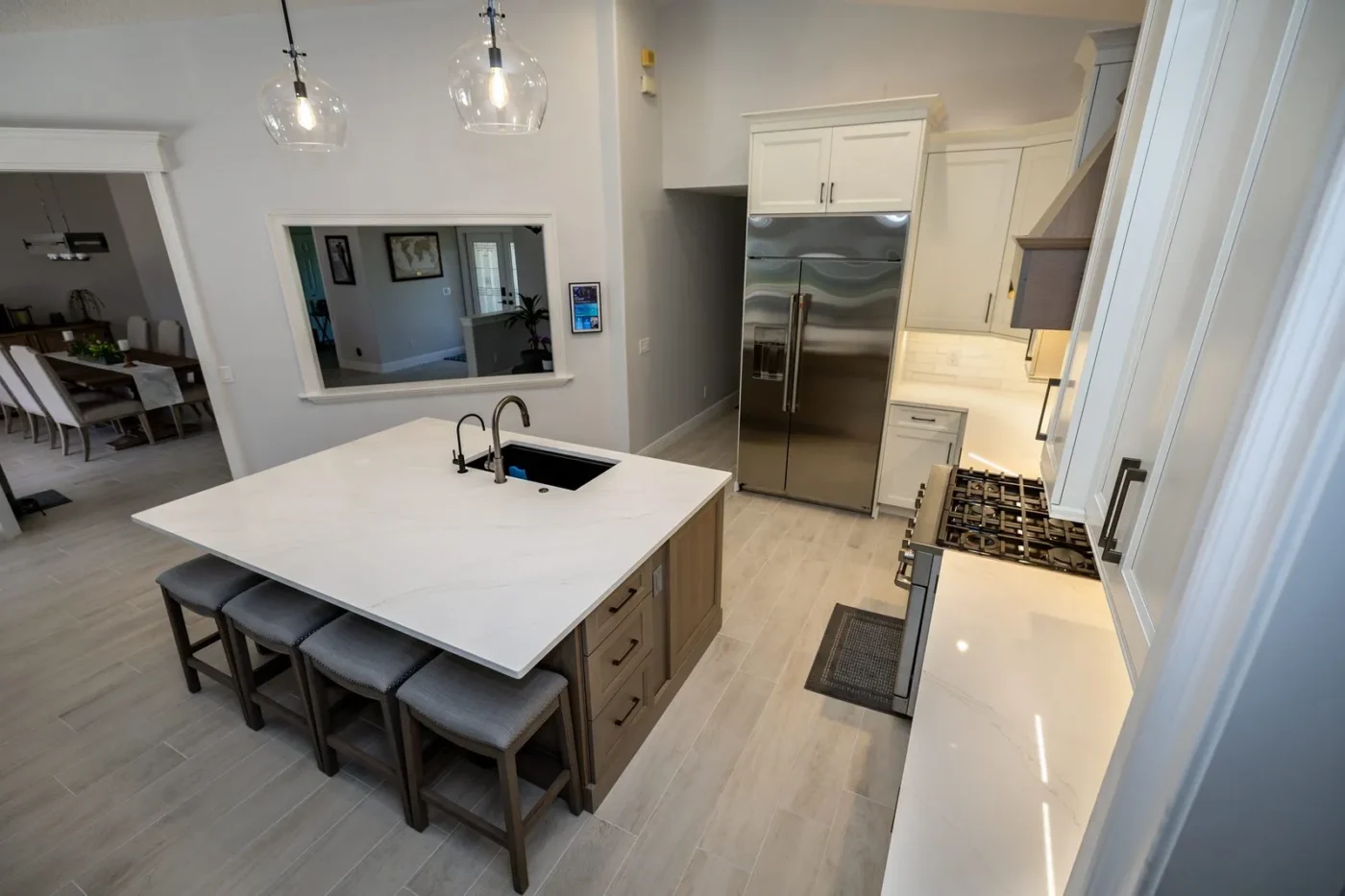 Square kitchen island with Vadara White Aurora quartz, seating for four, and a serving window to the dining room in a Lakewood Ranch FL remodel