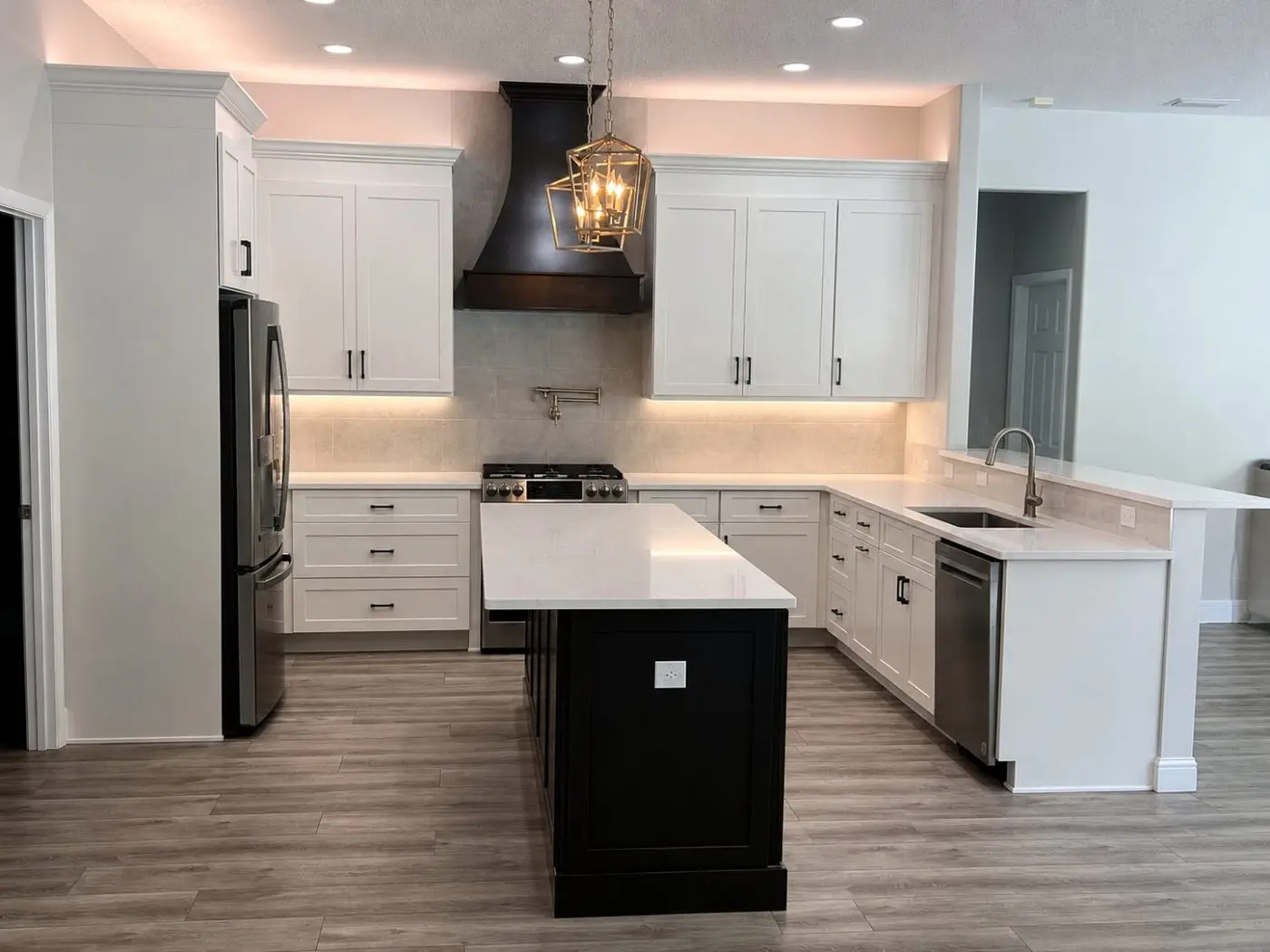 two tone kitchen cabinets with white shaker perimeter and espresso island under a black statement hood in a St Petersburg Florida remodel by CMK Construction