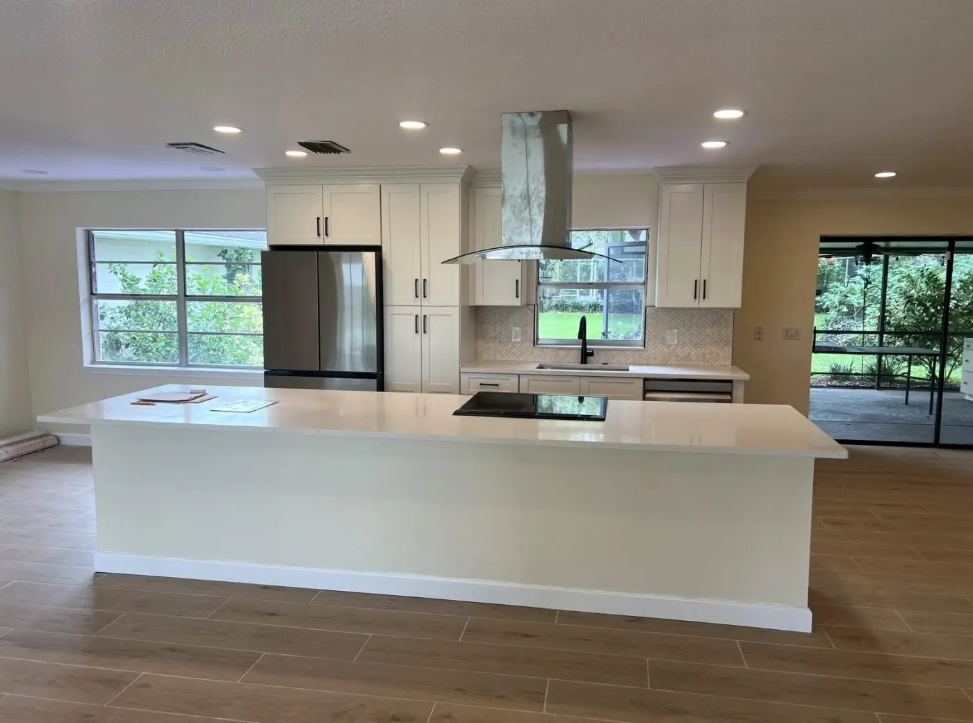 white kitchen with oversized island and island cooktop in seminole florida, fabuwood galaxy frost cabinets by cmk construction