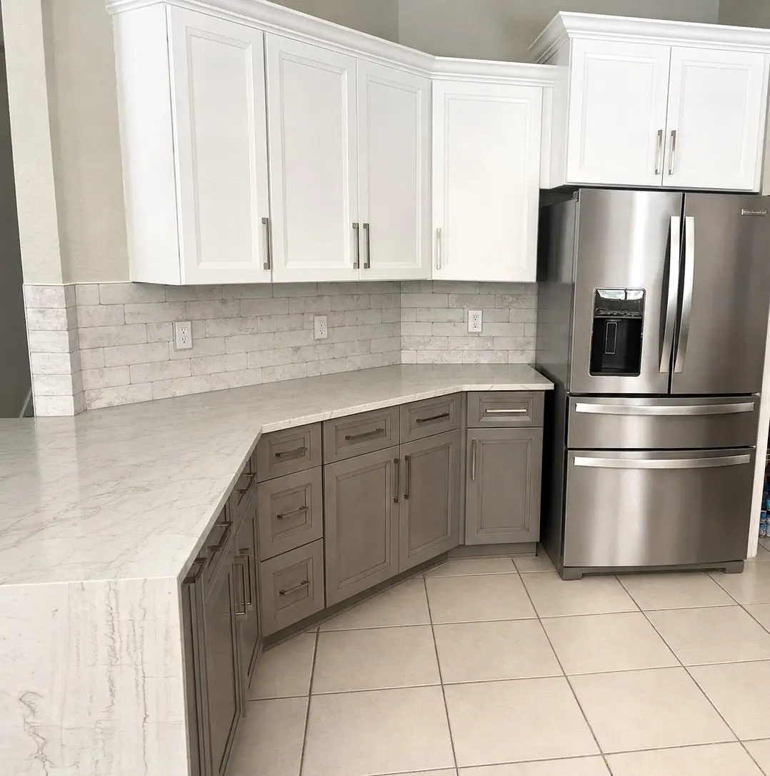two tone kitchen cabinets with white upper cabinets and greige lower cabinets and marble look brick backsplash in a South Tampa Florida remodel by CMK Construction